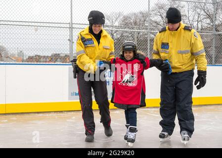 Les membres de la police de Toronto participent à l'ouverture officielle de la patinoire Regent Park; ils ont servi la communauté à aider les enfants à apprendre le ski de patinage Banque D'Images