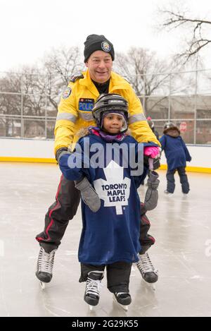 Les membres de la police de Toronto participent à l'ouverture officielle de la patinoire Regent Park; ils ont servi la communauté à aider les enfants à apprendre le ski de patinage Banque D'Images