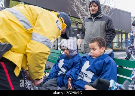 Les membres de la police de Toronto participent à l'ouverture officielle de la patinoire Regent Park; ils ont servi la communauté à aider les enfants à apprendre le ski de patinage Banque D'Images