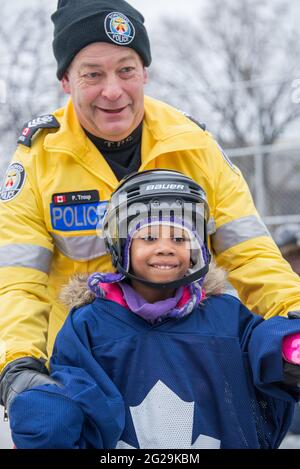 Les membres de la police de Toronto participent à l'ouverture officielle de la patinoire Regent Park; ils ont servi la communauté à aider les enfants à apprendre le ski de patinage Banque D'Images