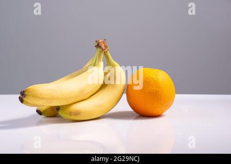 minimalisme des fruits bananes et orange sur fond blanc-gris. Banque D'Images