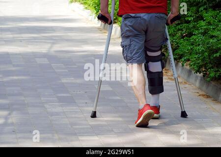 Violation du système musculo-squelettique. Blessures sportives. Fixation du support de la voûte plantaire sur la jambe. L'homme a des béquilles dans ses mains Banque D'Images