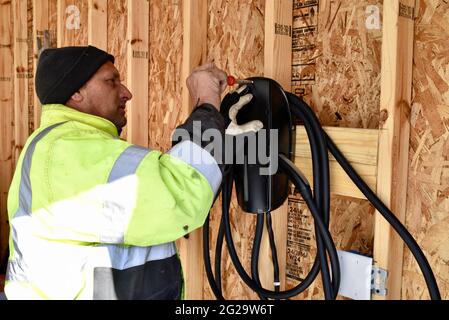 Électricien installant le chargeur Tesla monté à l'intérieur d'un garage dans une résidence privée utilisée pour recharger les véhicules électriques Tesla, Browntown WI, États-Unis Banque D'Images