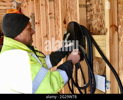 Électricien installant le chargeur Tesla monté à l'intérieur d'un garage dans une résidence privée utilisée pour recharger les véhicules électriques Tesla, Browntown WI, États-Unis Banque D'Images