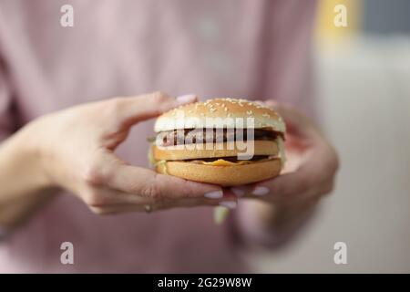 Femme tenant un délicieux hamburger appétissant dans ses mains en gros plan Banque D'Images