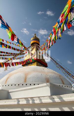 Vue sur le grand stupa blanc à Boudha, Katmandou. Il est drapé de drapeaux de prière colorés. Banque D'Images