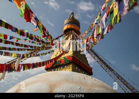 Vue rapprochée de la grande stupa blanche à Boudha, Katmandou, Népal. Des drapeaux de prière colorés ornent le bâtiment. Banque D'Images