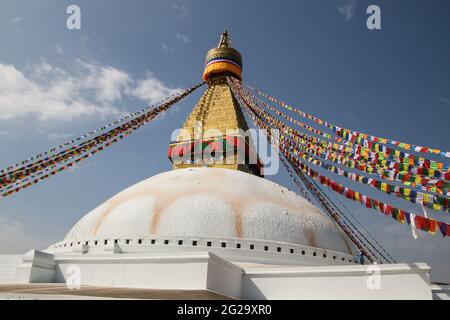 Vue rapprochée de la grande stupa blanche à Boudha, Katmandou, Népal. Des drapeaux de prière colorés ornent le bâtiment. Banque D'Images