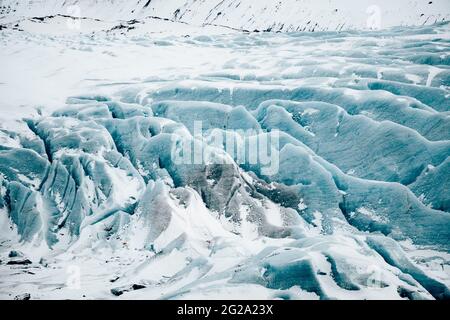 Depuis le dessus de la surface du sol gelé avec de la neige blanche et de la glace bleue sur la pente des montagnes en Islande Banque D'Images