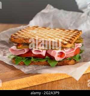 Délicieux sandwich, avec des arugula, des tomates et des concombres. Fines tranches de jambon frais. Une collation rapide. Mise au point sélective. Banque D'Images