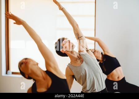 jeunes sportifs attrayants pratiquant la leçon de yoga dans une salle de formation lumineuse Banque D'Images