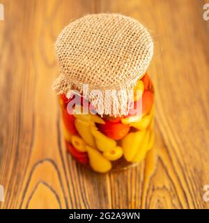 Poivre mariné dans un pot. Préparations faites maison de manière rustique. Un en-cas épicé. Noué avec un filetage en jute. Style rustique. Mise au point sélective. Banque D'Images