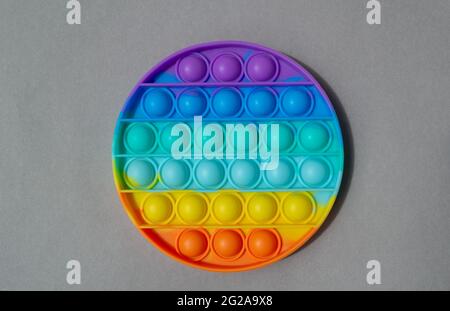 Jouet en silicone coloré brillant Pop IT. Jouet anti stress populaire sur fond gris Banque D'Images
