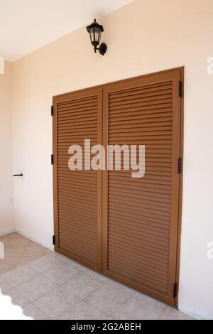 Volets de portes-fenêtres en bois brun avec lampe sur mur en pierre blanche. Complexe classique d'architecture grecque, bâtiment de maison sur la rive Banque D'Images