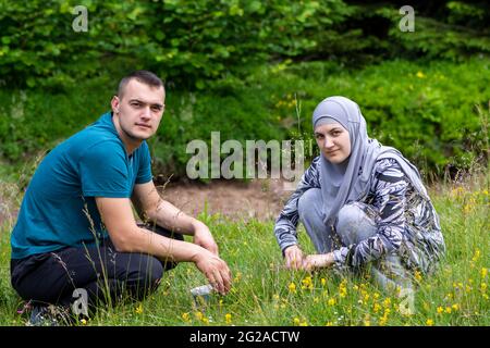 Un jeune couple musulman se squat sur l'herbe et regarde la caméra Banque D'Images