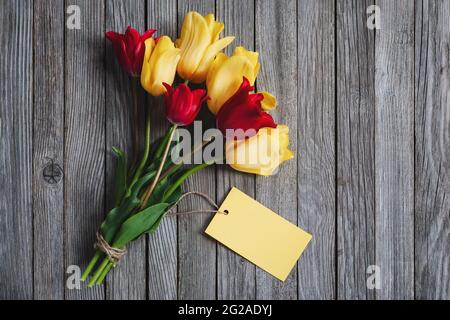 Bouquet de fleurs de tulipe avec carte de nom vierge sur fond en bois, espace de copie Banque D'Images