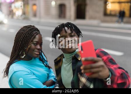 Un couple noir souriant prend un selfie dans la rue. Banque D'Images