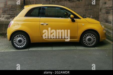 9 juin 2021 - Angleterre, Royaume-Uni: Fiat 500 jaune foncé garée à partir de l'ancien mur Banque D'Images