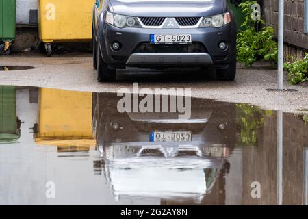 Riga, Lettonie, 26 mai 2021: Croisement Mitsubishi Outlander réflexion avant dans la cour flaque après la pluie, gros plan Banque D'Images