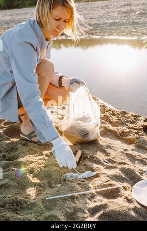 Femme ramasser les déchets de plastique sur la plage de sable de la mer. Des ordures ont été déversées sur la plage. Concept de pollution de l'environnement. Banque D'Images