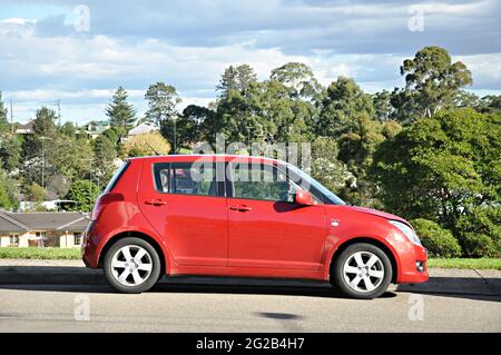 Petit parking rouge à côté de la rue. Banque D'Images
