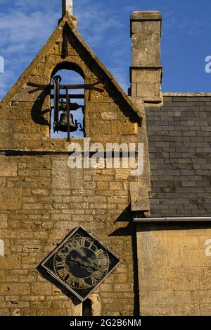 La tour de couvre-feu dans la ville de Moreton-in-Marsh, dans les Cotswold, dans le Gloucestershire, en Angleterre, au Royaume-Uni, date probablement des années 1500 et est l'une des rares structures de ce type à survivre. Il a une ancienne cellule de prison ou de prison à sa base, une horloge de 1648 et une cloche de couvre-feu de 1633 qui a été sonné tous les soirs jusqu’en 1860 pour avertir les résidents de « couvrir le feu » la nuit – essentiel dans un endroit où la plupart des maisons en pierre de couleur miel avaient des toits de chaume hautement inflammables. La tour à pignons se trouve à la jonction d'Oxford Street et High Street. Banque D'Images