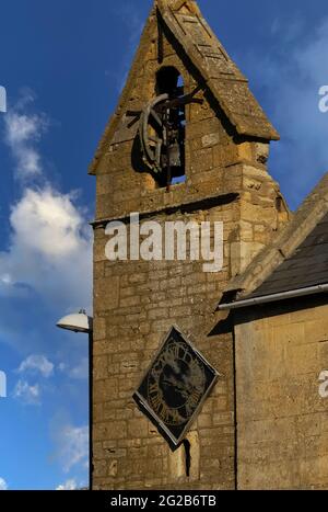La tour de couvre-feu à pignons dans la ville de Moreton-in-Marsh dans les Cotswold, Gloucestershire, Angleterre, Royaume-Uni, date probablement des années 1500 et est l'une des rares structures de ce type à survivre. Il a une ancienne cellule de prison ou de prison à sa base, une horloge de 1648 et une cloche de couvre-feu de 1633 qui a été sonné tous les soirs jusqu’en 1860 pour avertir les résidents de « couvrir le feu » la nuit – essentiel dans un endroit où la plupart des maisons en pierre de couleur miel avaient des toits de chaume hautement inflammables. La tour se trouve à la jonction d'Oxford Street et High Street. Banque D'Images