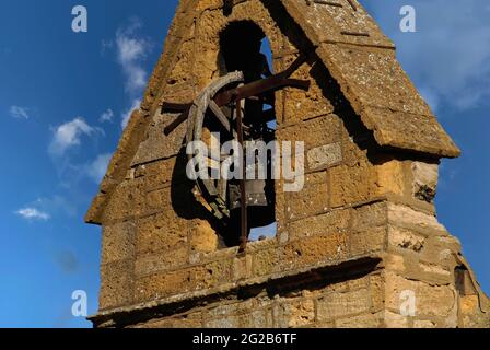 Une cloche coulée en 1633, attachée à une poulie en bois, est suspendue dans la tour de couvre-feu à pignon surplombant la place du marché à Moreton-in-Marsh, Gloucestershire, Angleterre, Royaume-Uni. Il a été sonné tous les soirs jusqu’en 1860 pour avertir les résidents de « couvrir le feu » la nuit – ce qui est essentiel lorsque la plupart des bâtiments en pierre de couleur miel de la ville des Cotswold étaient couverts de chaume inflammable. La tour date probablement des années 1500 et est une survie rare de ce type. Il dispose d'une cellule de prison au niveau du sol et d'une horloge de 1648. Banque D'Images