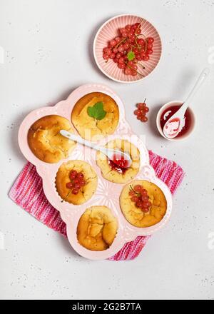 Vue de dessus des petits gâteaux faits maison au fromage avec des baies de cassis et de la confiture dans un moule à muffins en céramique. Copier l'espace. Banque D'Images