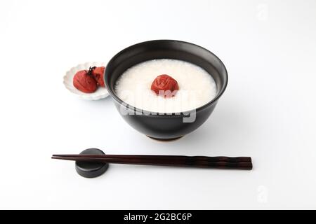 porridge de riz avec prune marinée au sel dans des baguettes de bol isolées sur fond blanc Banque D'Images