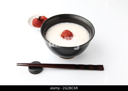 porridge de riz avec prune marinée au sel dans des baguettes de bol isolées sur fond blanc Banque D'Images