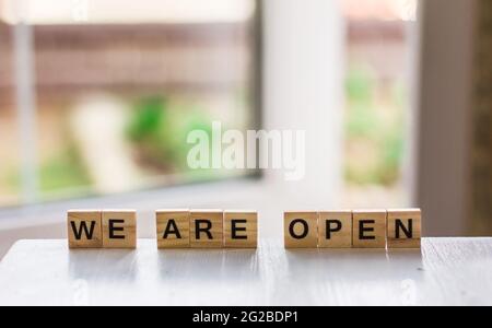 Le mot « We are open » fait de cubes de bois sur le fond d'une porte ouverte, fin de quarantaine un café, un magasin local, en accueillant les clients après le Banque D'Images