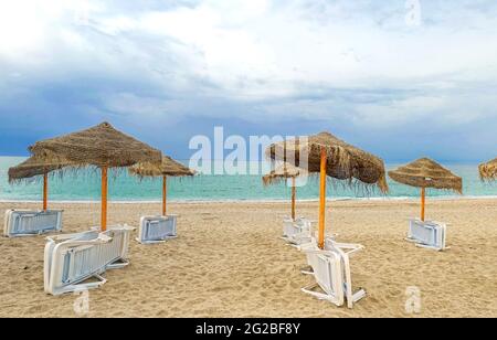 chaises longues en plastique blanc, parasols sur la plage. Banque D'Images