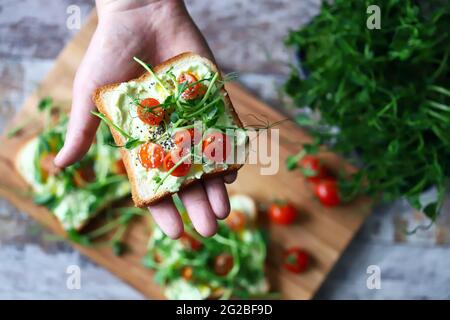 Toasts avec des microverts. La main contient un pain grillé sain. Un homme mange un pain grillé avec des micro-verts. Concept d'alimentation saine. Super cuisine. Banque D'Images