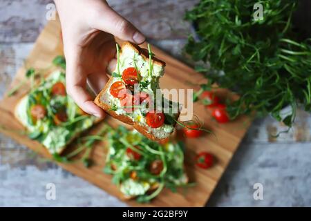 Toasts avec des microverts. La main contient un pain grillé sain. Un homme mange un pain grillé avec des micro-verts. Concept d'alimentation saine. Super cuisine. Banque D'Images