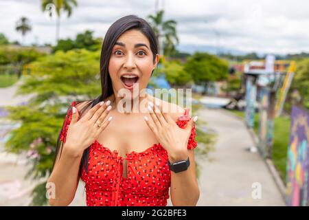 Belle jeune femme surprise montrant les mains et l'anneau d'engagement. Banque D'Images