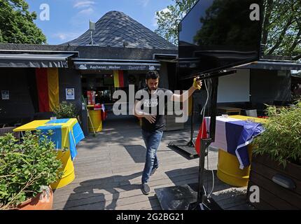 Cologne, Allemagne. 10 juin 2021. Un employé installe un écran de télévision dans le café en plein air de Aachener Weiher. Le championnat d'Europe de football commence, mais la crise de Corona n'est pas encore terminée. Les fans de football vont devoir se passer d'événements publics de grande envergure cette année. Et les règles de distance s'appliquent également dans les bars et les jardins de bière. (À dpa: 'Biergarten statt Festplatz: We Menschen in Nordrhein-Westfalen die Fußball-EM in der Pandemie schauen') Credit: Oliver Berg/dpa/Alay Live News Banque D'Images