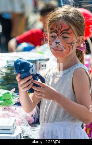 Scènes du festival Little Portugal. Petite fille avec son visage peint comme un tigre, tenant un jouet doux. Le festival Little Portugal est une Ann animée Banque D'Images