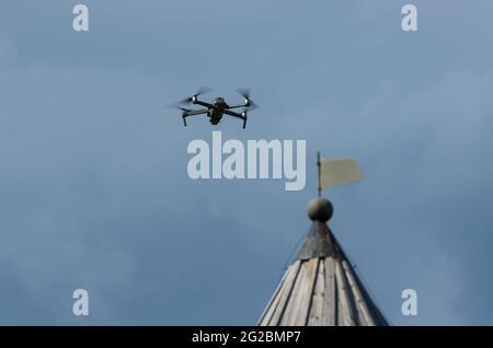 Voler un drone quadricoptère contre le ciel bleu en arrière-plan le toit d'une ancienne tour (Staraya Ladoga, Saint-Pétersbourg, Russie) Banque D'Images