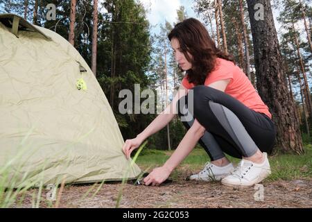 La fille assemble une tente de camping. Voyagez en dehors de la ville dans les bois. Camping. Banque D'Images