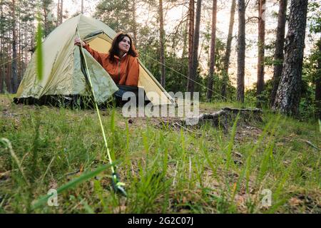 La fille sort de la tente après avoir dormi. Voyagez en dehors de la ville dans les bois. Camping. Banque D'Images