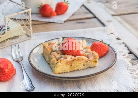 Morceau de gâteau de crumble de rhubarbe et de fraises sur une assiette sur une table en bois Banque D'Images