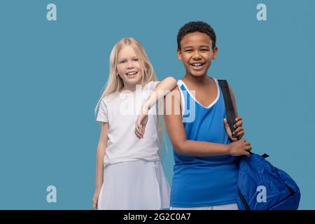 Des enfants heureux dans des vêtements de sport sur fond bleu Banque D'Images