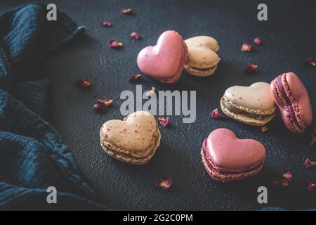 Macarons en forme de cœur sur fond bleu foncé Banque D'Images