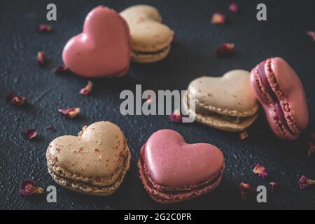 Macarons en forme de cœur sur fond bleu foncé Banque D'Images