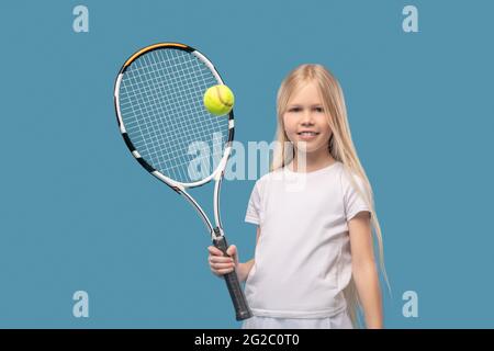 Joyeux joueur de tennis en adolescence qui frappe le ballon avec la raquette Banque D'Images