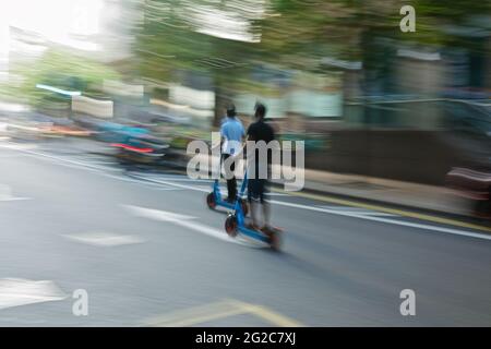 Londres (Royaume-Uni), 10 juin 2021 : deux pilotes de scooter électrique sont vus sur les routes de la région des Docklands à Londres. Banque D'Images