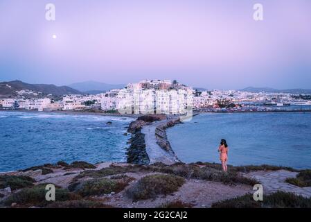 La jeune femme bénéficie de la vue sur la lune au-dessus de l'île de Naxos au coucher du soleil, en Grèce. Banque D'Images