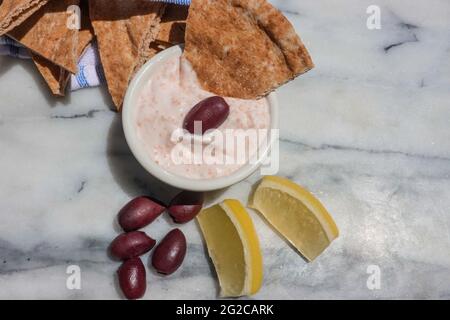 Pain de taramosalata Pita, olives de kalamata et quartiers de citron sur une cuisine en marbre. Banque D'Images