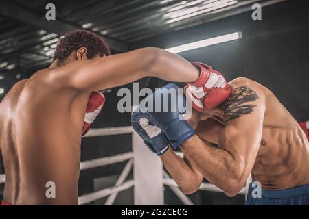 Deux kickboxers se battent sur un ring de boxe et ont l'air agressif Banque D'Images